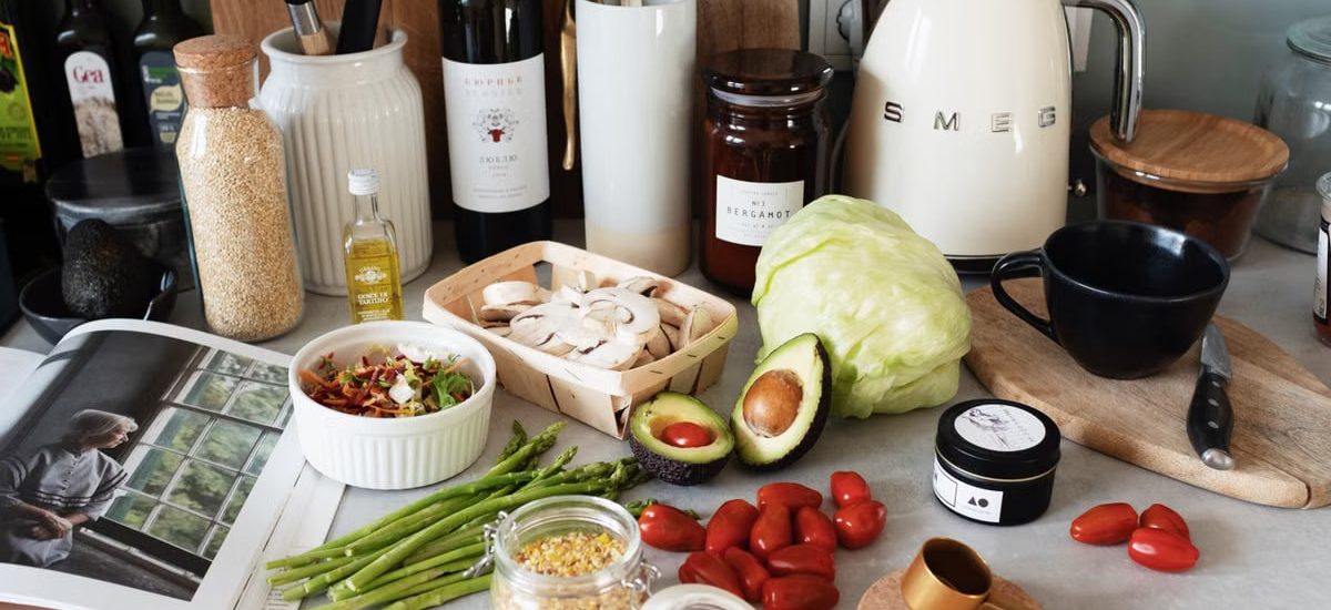Assorted healthy food and vegetables set locating on gray countertop next to various utensils and appliances during cooking in stylish kitchen