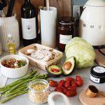 Assorted healthy food and vegetables set locating on gray countertop next to various utensils and appliances during cooking in stylish kitchen