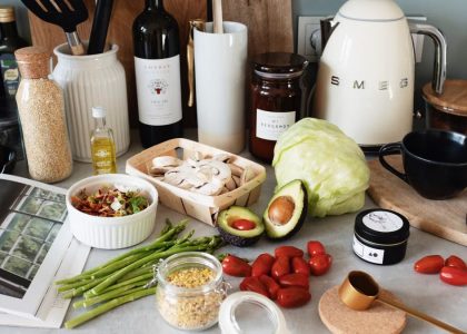 Assorted healthy food and vegetables set locating on gray countertop next to various utensils and appliances during cooking in stylish kitchen